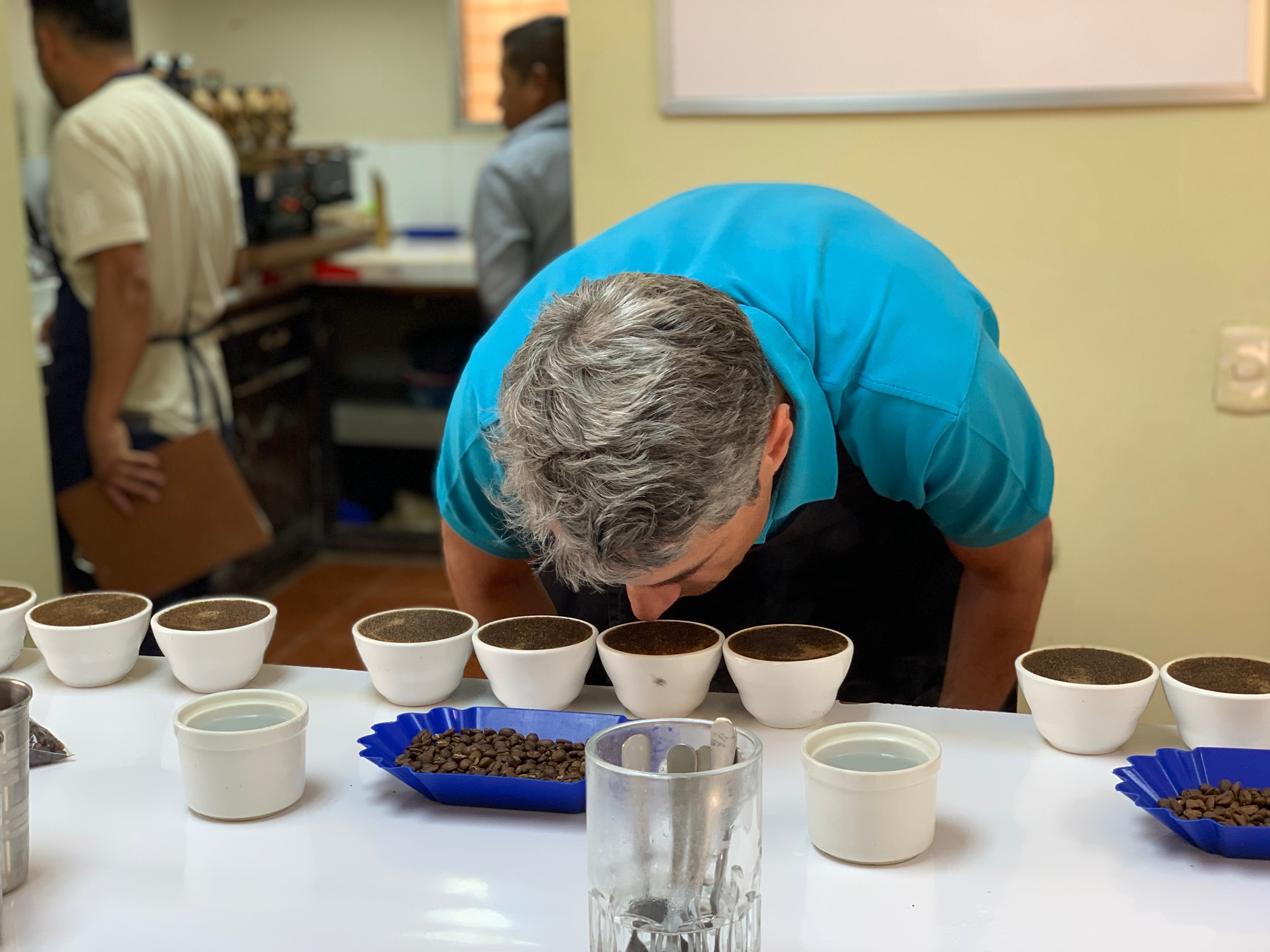 A man in blue shirt cupping coffee on a table