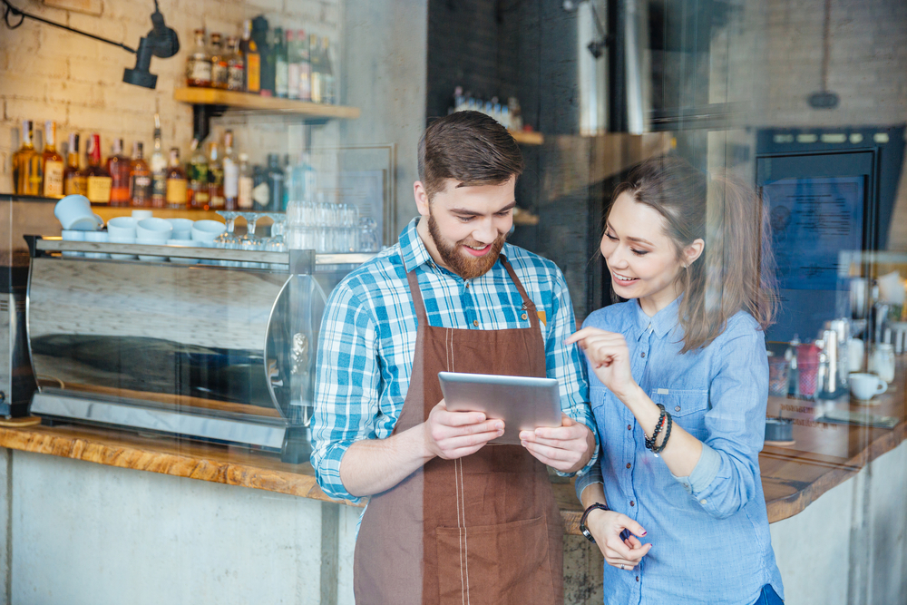 A picture of barista and customer in a coffeeshop reading a tablet